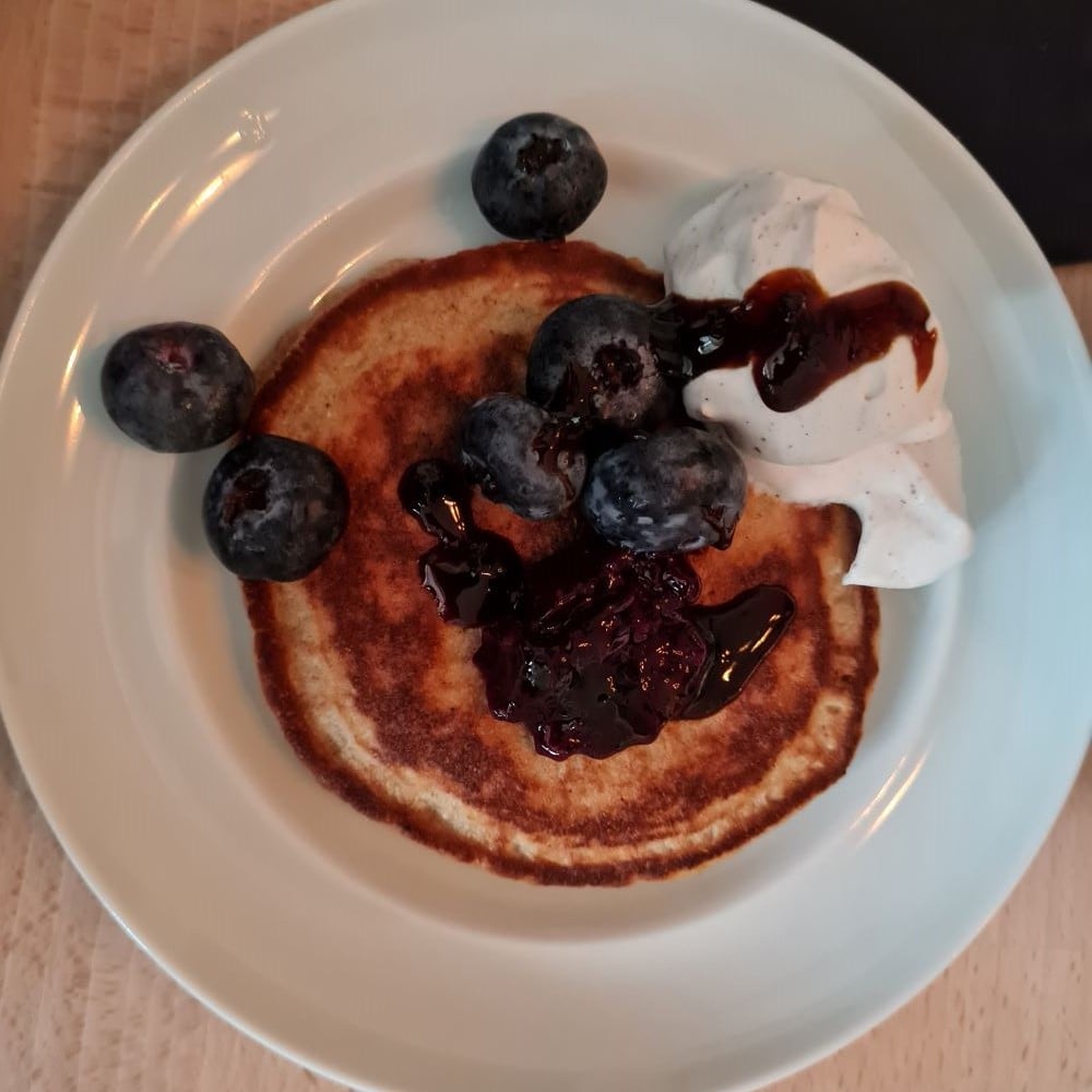 Keto-Pandekage m havreflødeskum, Sukrin eller Yacon-sirup og bær på hvid kagetallerken