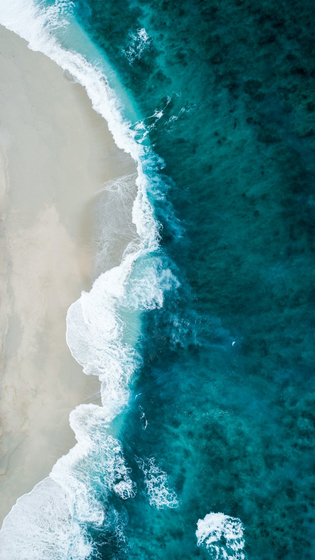 Stress-håndtering ved kræft symboliseret ved detalje af voldsom brænding fra hav skyller ind over en fin sandstrand.