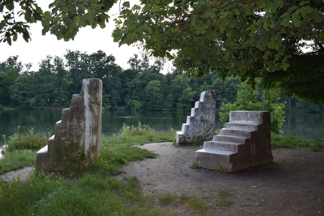 Cancerpakken af Milena Penkowa symboliseret ved en plads i skov ved skovsø. På pladsen er stenskulpturer der forestiller trapper.
