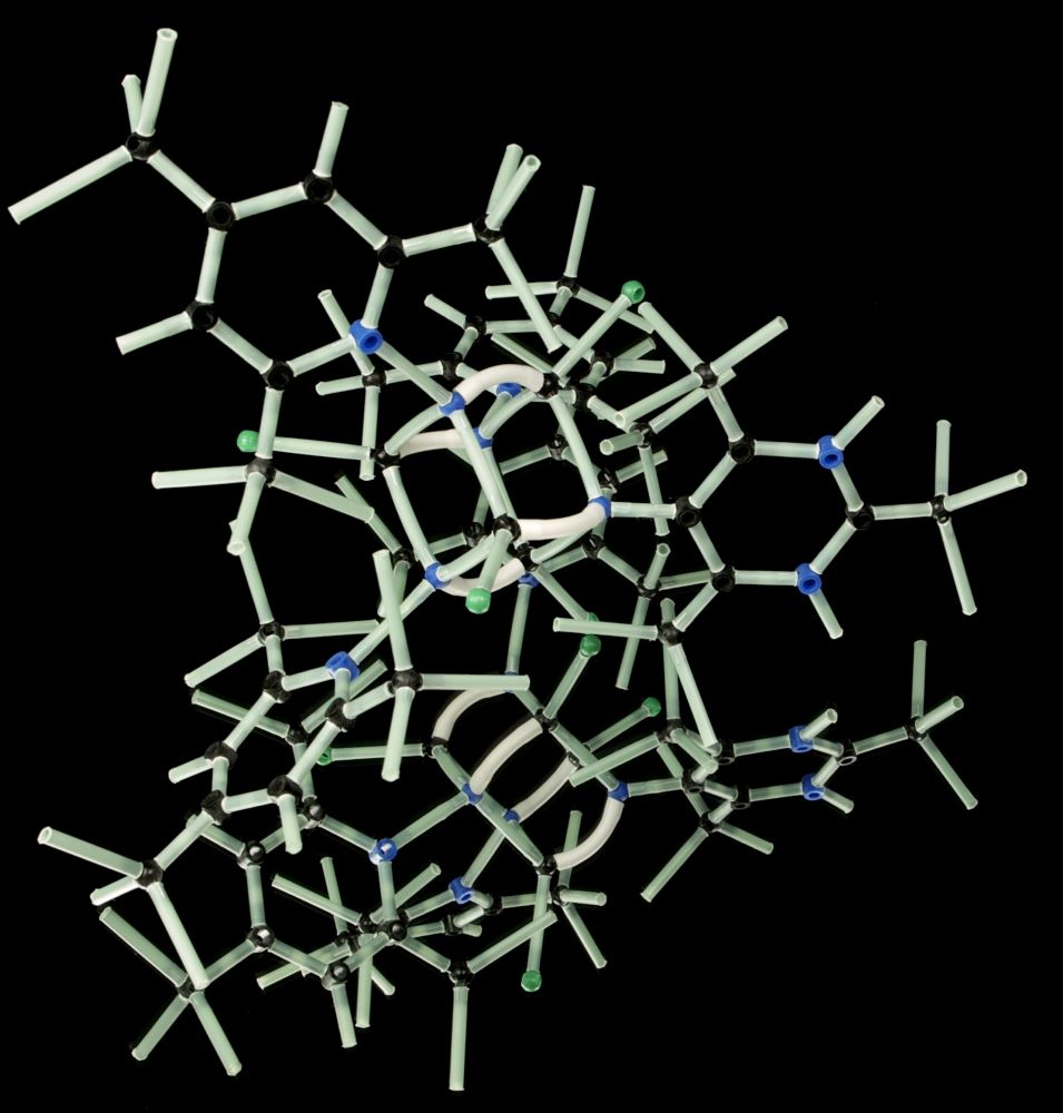 KRAS-mutation symboliseret ved tændstikagtige elementer, der sammen danner en kompleks åben figur. Hvide strenge på sort baggrund.