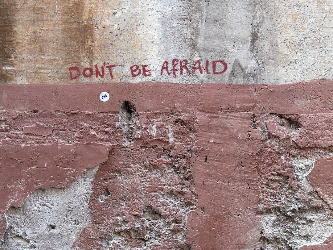 Praktiske råd til kræftramte symboliseret ved en gammel-rosa-tonet pudset mur med teksten: Don't be afraid - vær ikke bange.