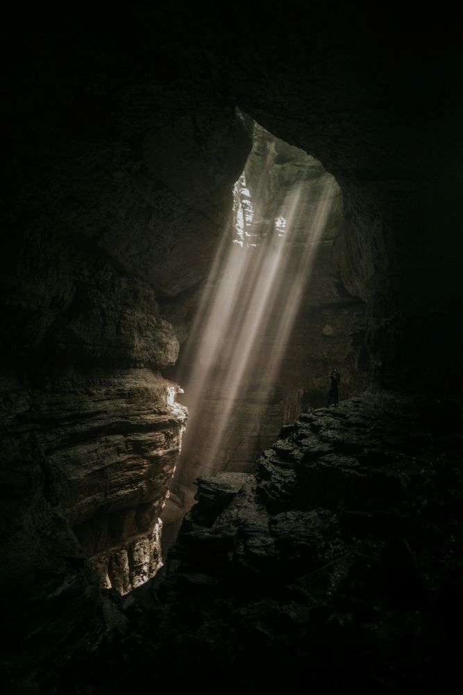 SIRT Strålebehandling symboliseret ved lysstråler der når ned i dybet af en grotte.