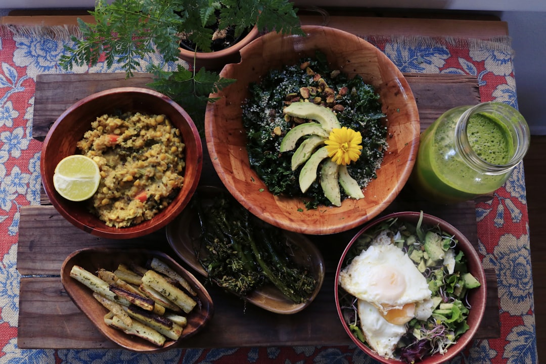 Ayurvedisk Kost symboliseret ved foto af brune skåle i forskellig størrelse med eksotiske retter. Ved siden af står et glas med en grøn dressing eller juice.