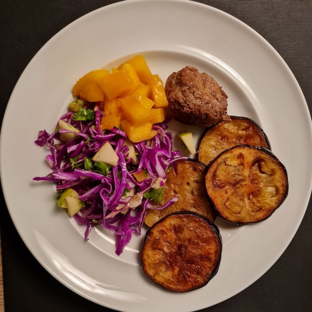 Kyllingfrikadelle m. stegt aubergine og rød spidskålssalat m mango, persille og æble på hvid tallerken.