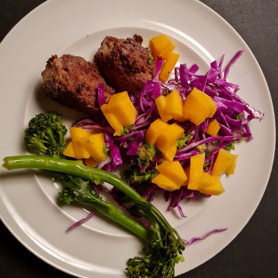 Kyllingfrikadeller m rød spidskål, mango, knuste wasabinødder, aspargesbrokkoli på hvid tallerken.