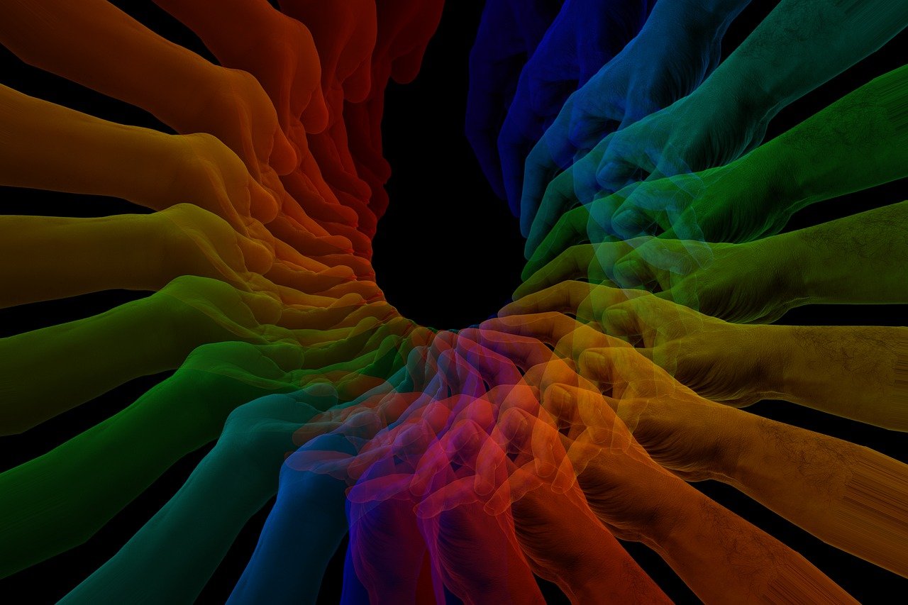 Pårørende symboliseret ved fremstrakte håbdflader der samlet danner en mørk cirkel i midten. Der er alle regnbuens farver hen over billedet - i dæmpede toner.