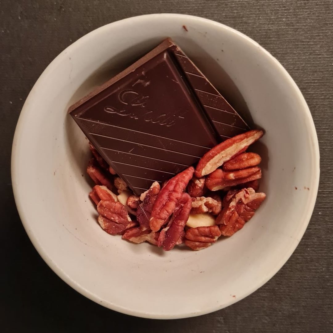 Pekannødder og mørk chokolade i lille hvid skål.