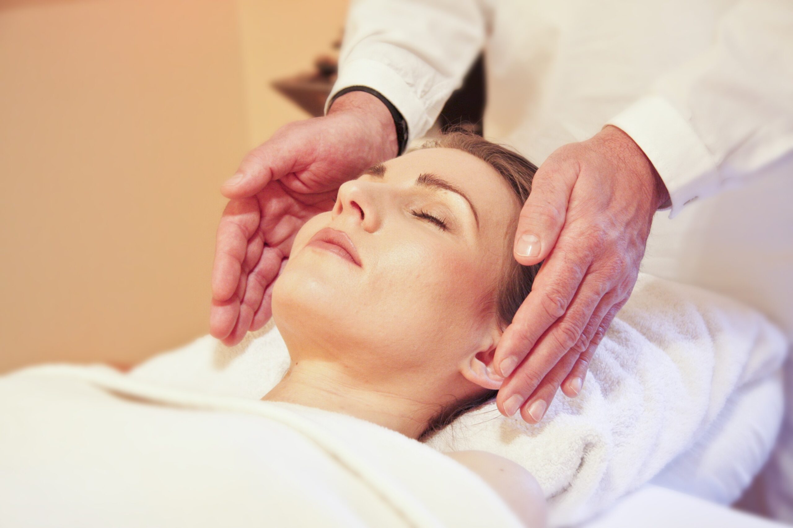 Reiki healing symboliseret ved en kvinde, der bliver healet af to hænder. En på hver side af hendes ansigt.