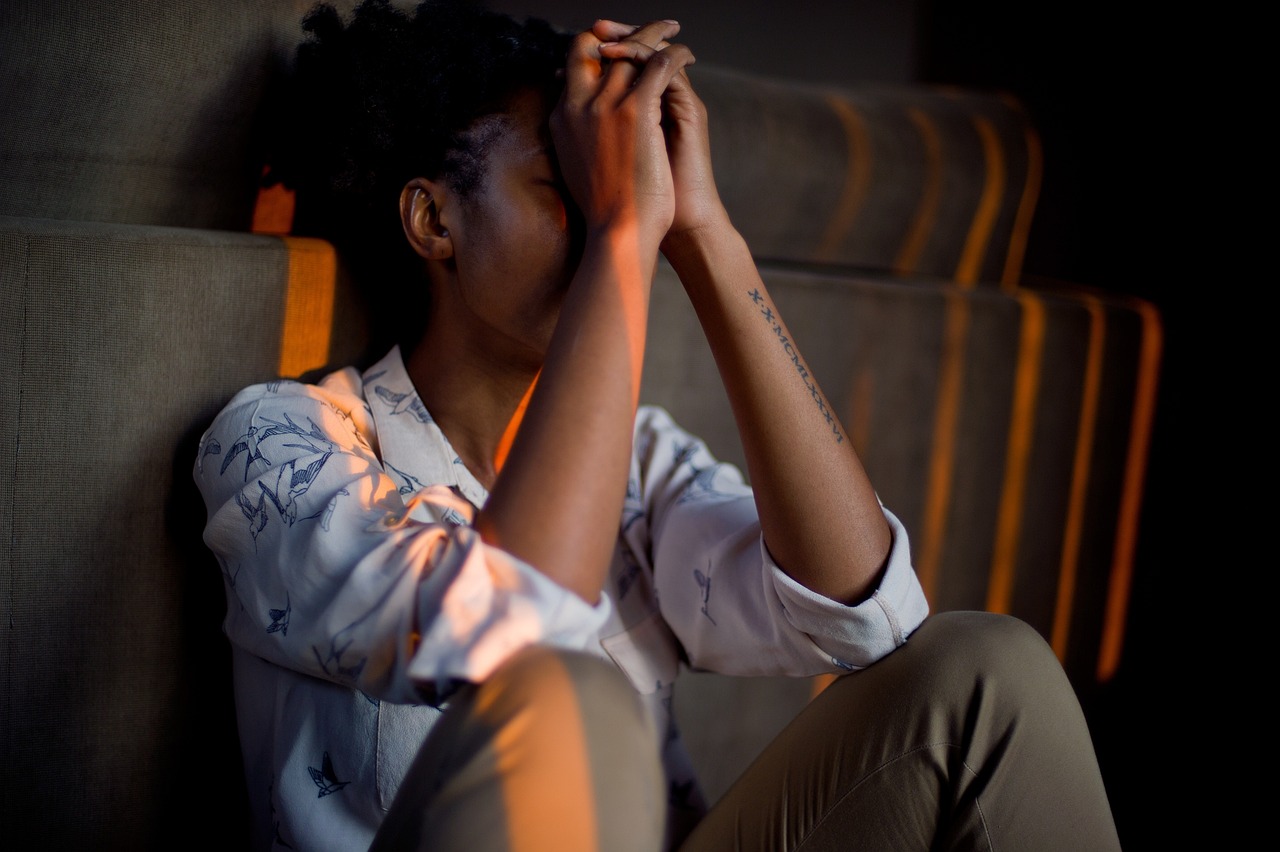 Stress symboliseret ved mand der sidder på gulv med bøjede ben og hænderne op foran ansigtet.
