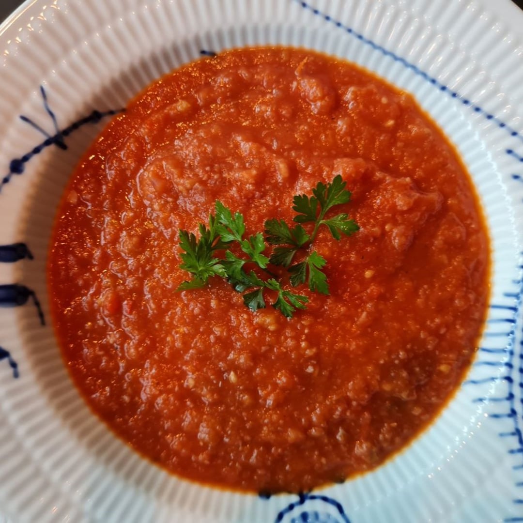 Tomatsuppe i dyb mega musselmalet tallerken. På toppen en lille dusk persille.