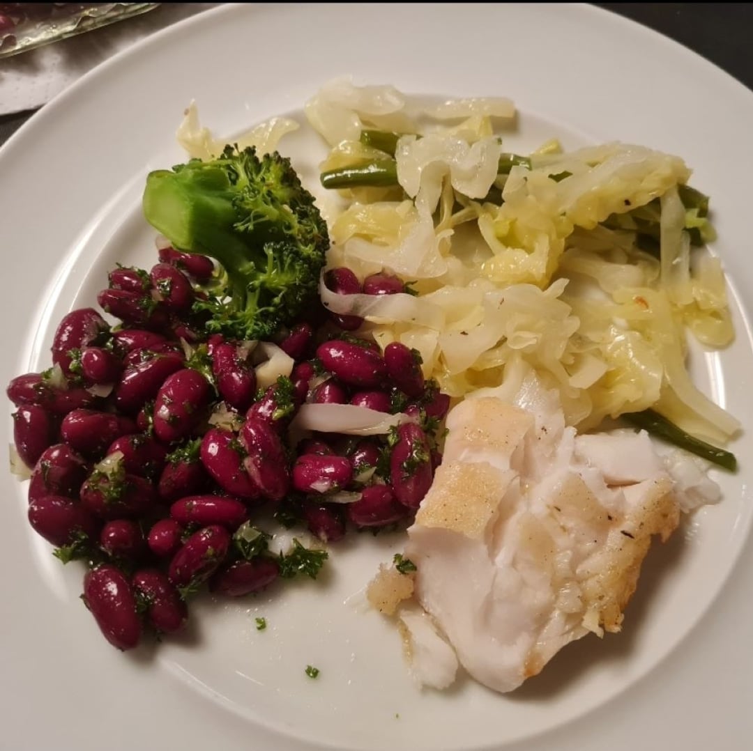 Torsk m stuvet kål, grønne bønner, brokkoli og kidneybønnesalat på hvid tallerken.