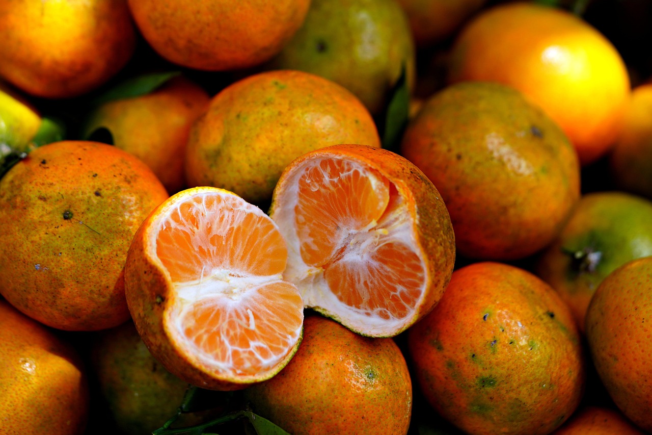 Vitamin-C oralt symboliseret ved en overskåret citrusfrugt, der ligger ovenpå flere andre.