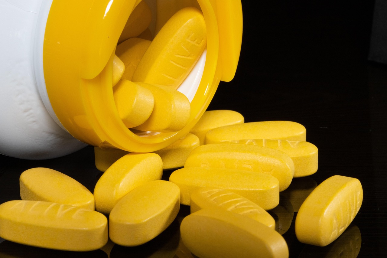 Vitamin-C oralt symboliseret ved en pillebøtte der ligger ned og gule aflange piller der ligger foran.