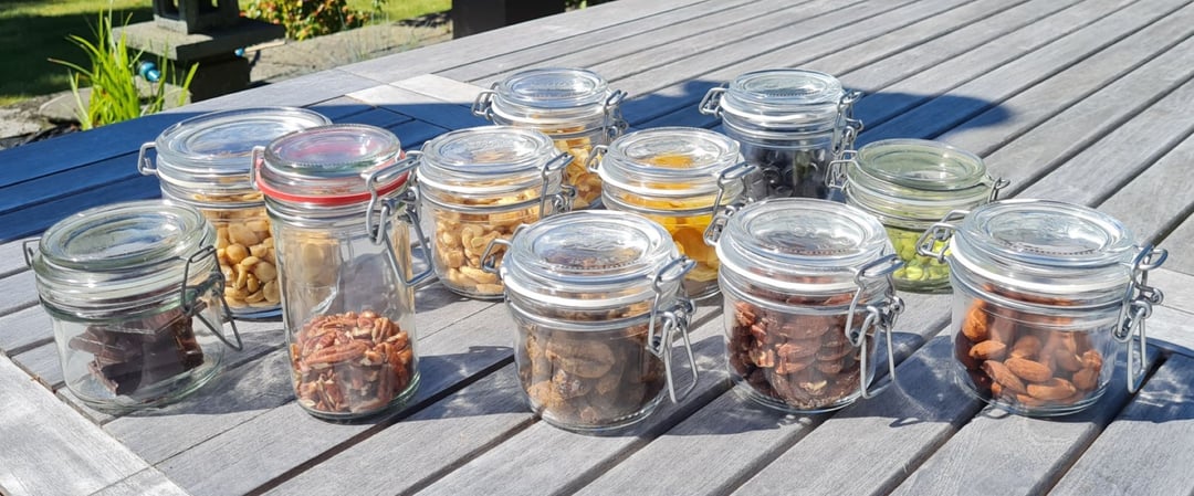 Samling af snaks i små patentlågsglas på terrassebord.