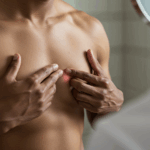 Brystkræft hos mænd symboliseret ved overkrop af mand, der med hænderne undersøger sit brystområde.