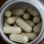 Magnesium illustreret ved hvidt bæger med lyse kapsler, der forestiller at indeholde magnesium.