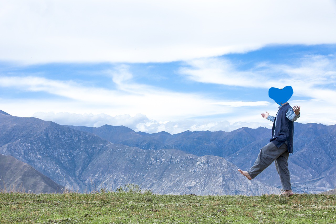 Naturhealing symboliseret ved billede af barfodet mand der går i græs. I baggrunden ses bjerge og blå himmel.