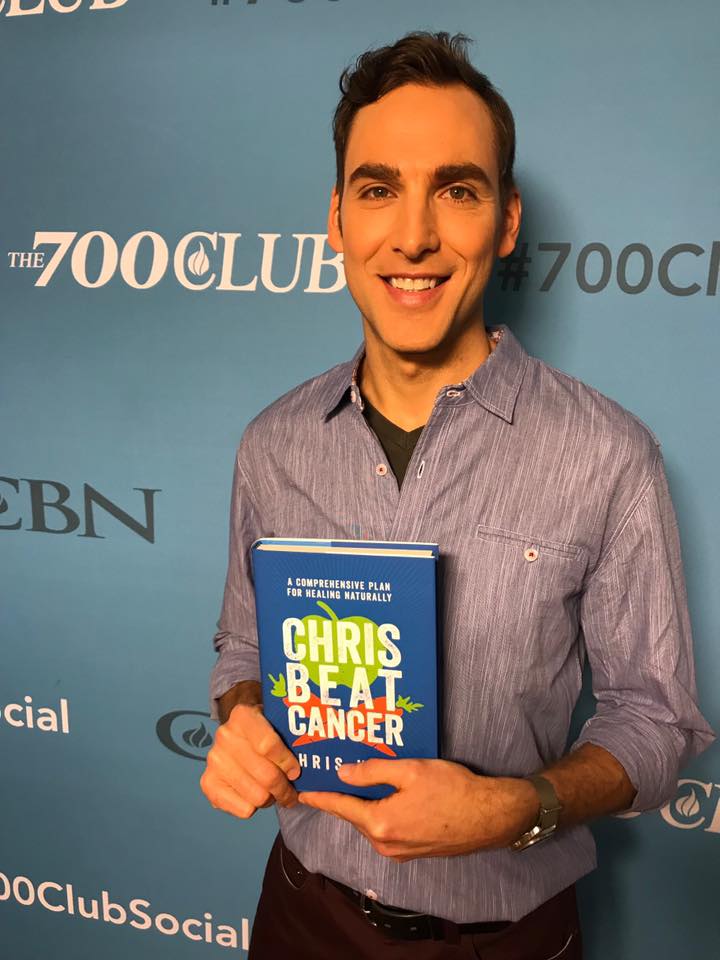 Chris Beat Cancer symboliseret ved foto af Chris fra en bogudgivelse. Man ser hans overkrop og ansigt. Han holder sin bog frem.