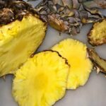 Kræftens forsyningsveje symboliseret ved foto af ananas, der er delvis opskåret i skiver. Liger på gråt underlag.