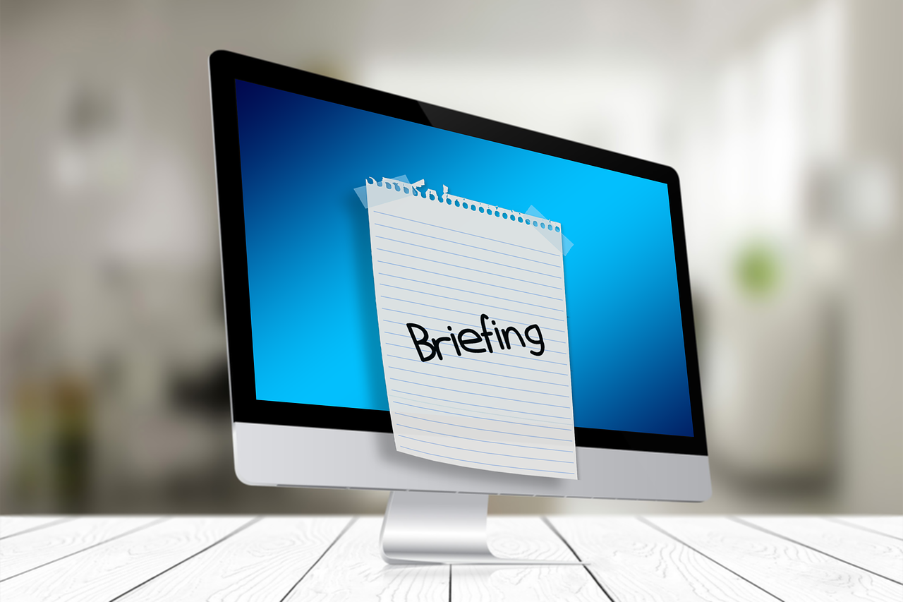Guide til sitet symboliseret ved en pc med blå skærm og en seddel tapet på, hvor der står Briefing