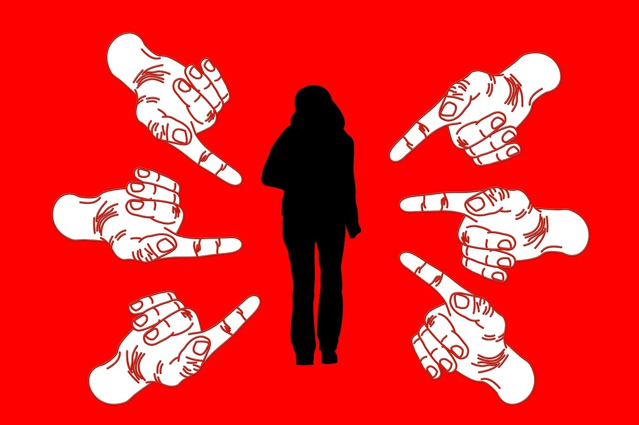 Skyld og skam symboliseret ved silhuetten af en person og 6 hænder der fra alle sider peget mod personen. Rød baggrund.