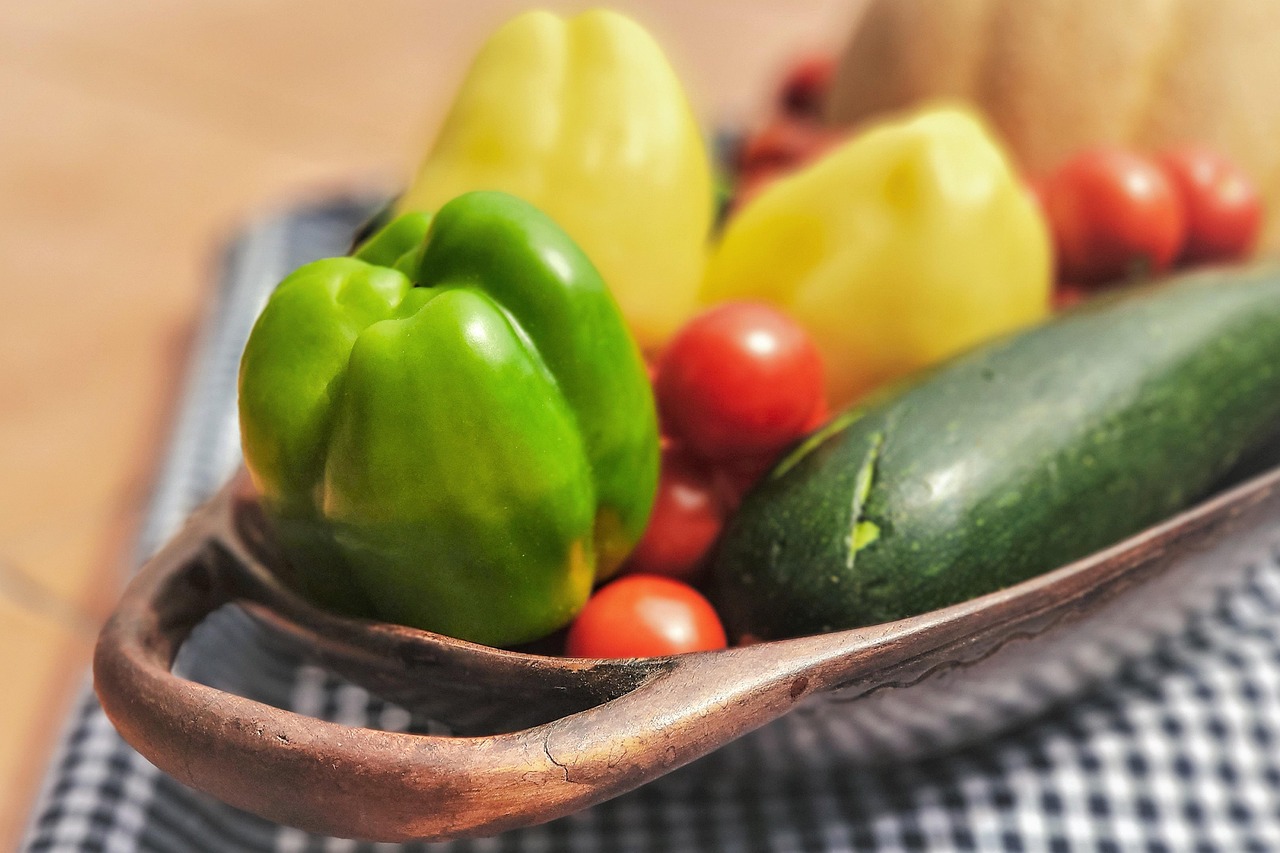 Dæmp inflammation symboliseret ved nogle grøntsager på et fad. Grøn peber, gul peber, squash og tomater. Ternet dug.