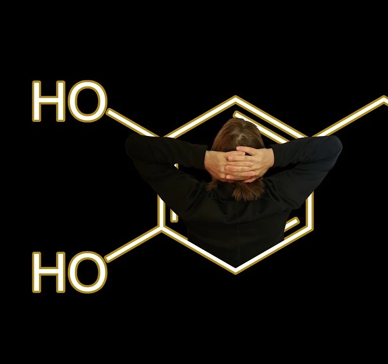 Hormonforstyrrende stoffer symboliseret ved del af molekyle, hvor der til venstre står HO to steder og i midten ses en kvinde oppefra. Sort baggrund.