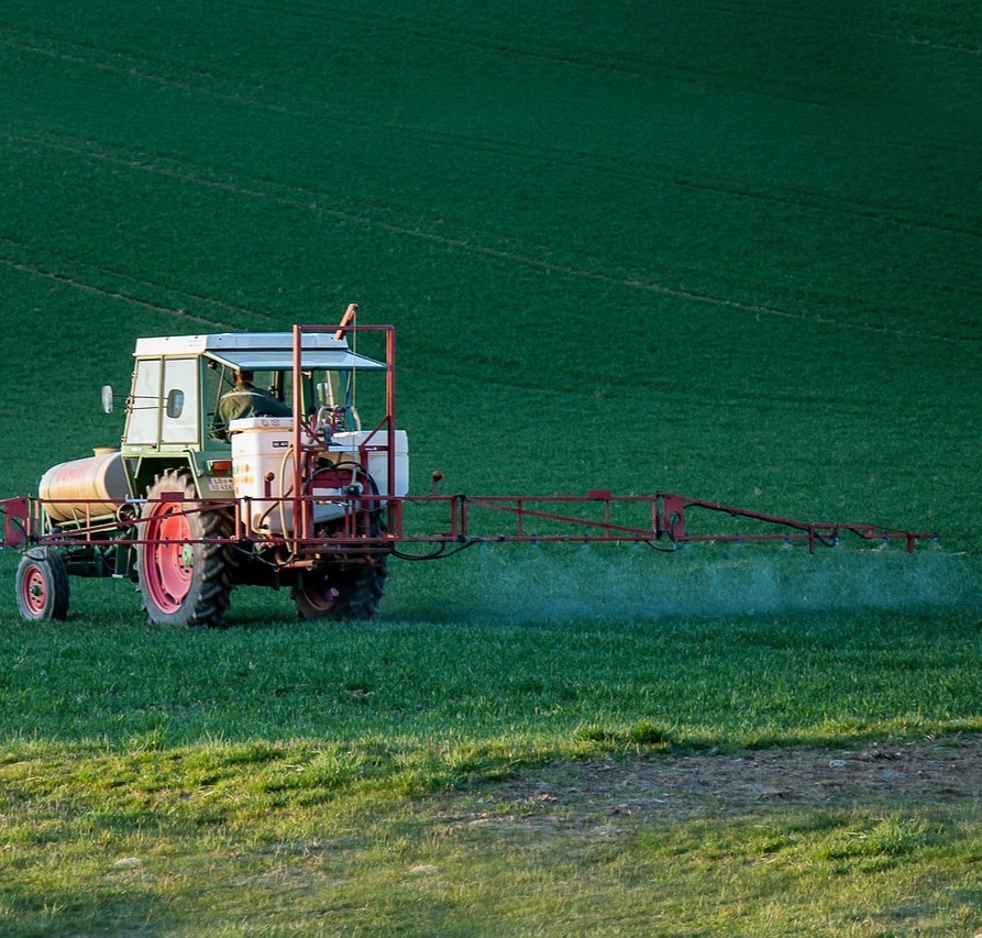 Pesticider symboliseret ved traktor der sprøjter marker.