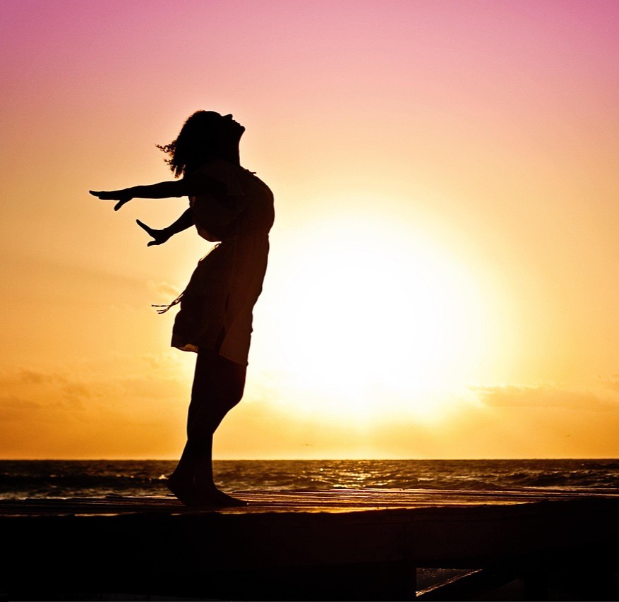 Placebo- og nocebo effekten symboliseret ved en kvindesilhuet der strækker sig i solopgangen med en positur som hun kan overvinde alt.