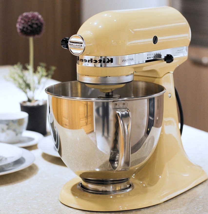 Køkkenudstyr, madopbevaring og emballage symboliseret ved en dejrøremaskine med skål i rustfri stål.