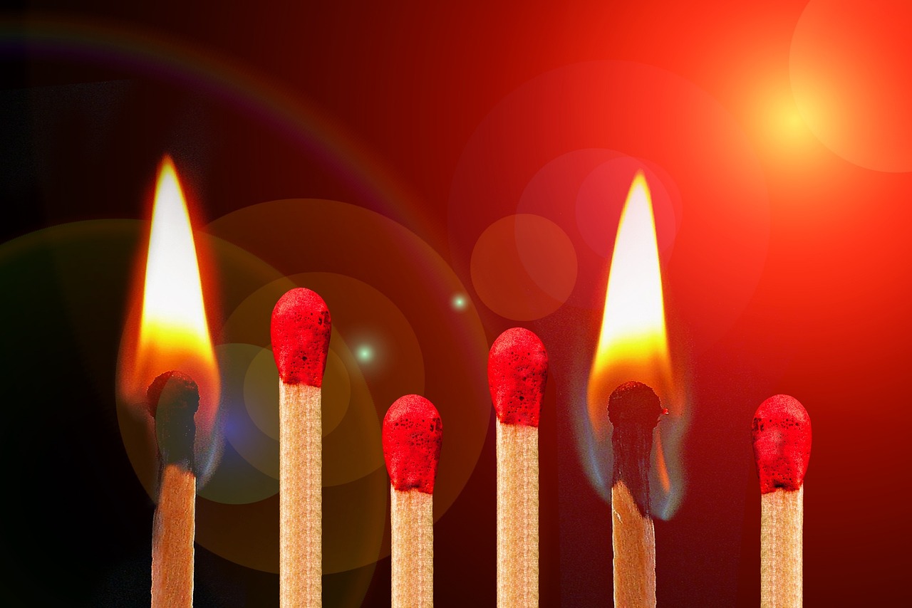 Lindre smerter med kost symboliseret ved foto af 5 lodrette tændstikker med rødt svovl. de to yderste er tændte og brænder. Rød baggrund.