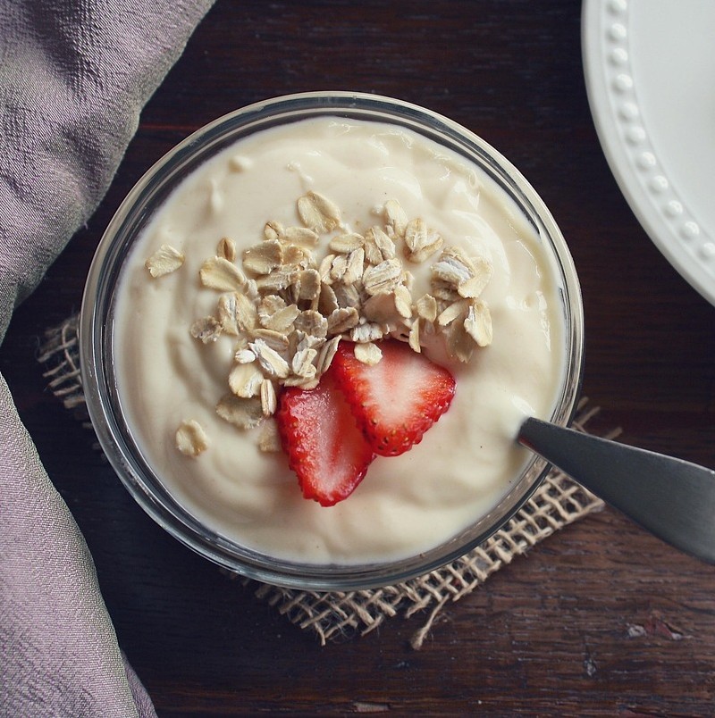 Mejeriprodukter og kræft symboliseret ved en skål yoghurt med havregryn og et par skiver jordbær.
