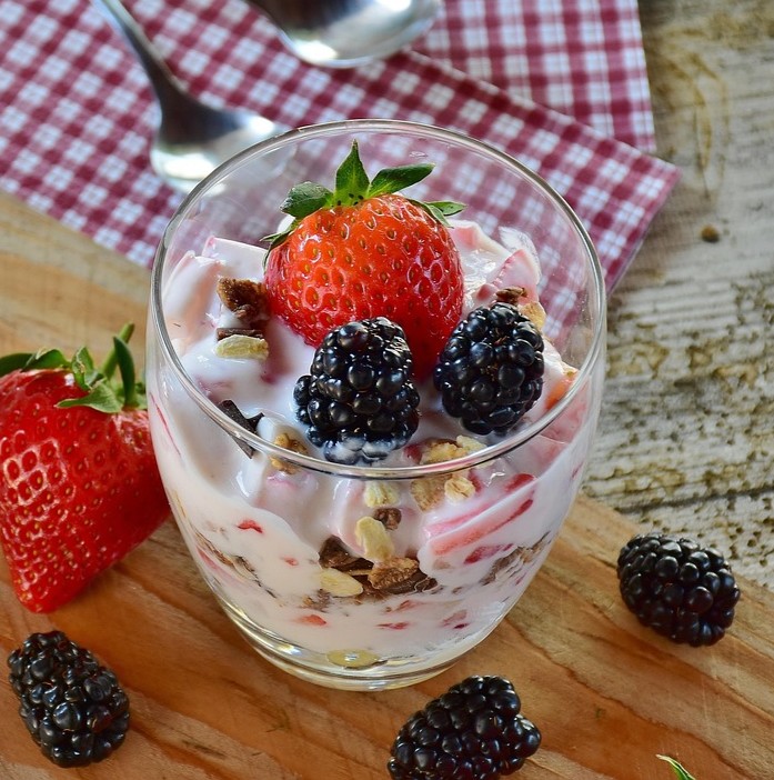 Mejeriprodukter og kræft symboliseret ved et glas med en mælkedessert toppet med jordbær og brombær