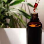 Antioxidanter - for og imod symboliseret ved en plante i baggrunden og et brun flaske med en pipette, der har opsamlet en brun væske.