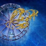 Endetarmskræft symboliseret ved et ur med stjernetegn, en gul tegning af en krebs i streg. Blå baggrund.