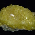 MSM. Methylsulfonylmethan - svovl - symboliseret ved et stykke med gule krystaller. Sort baggrund.