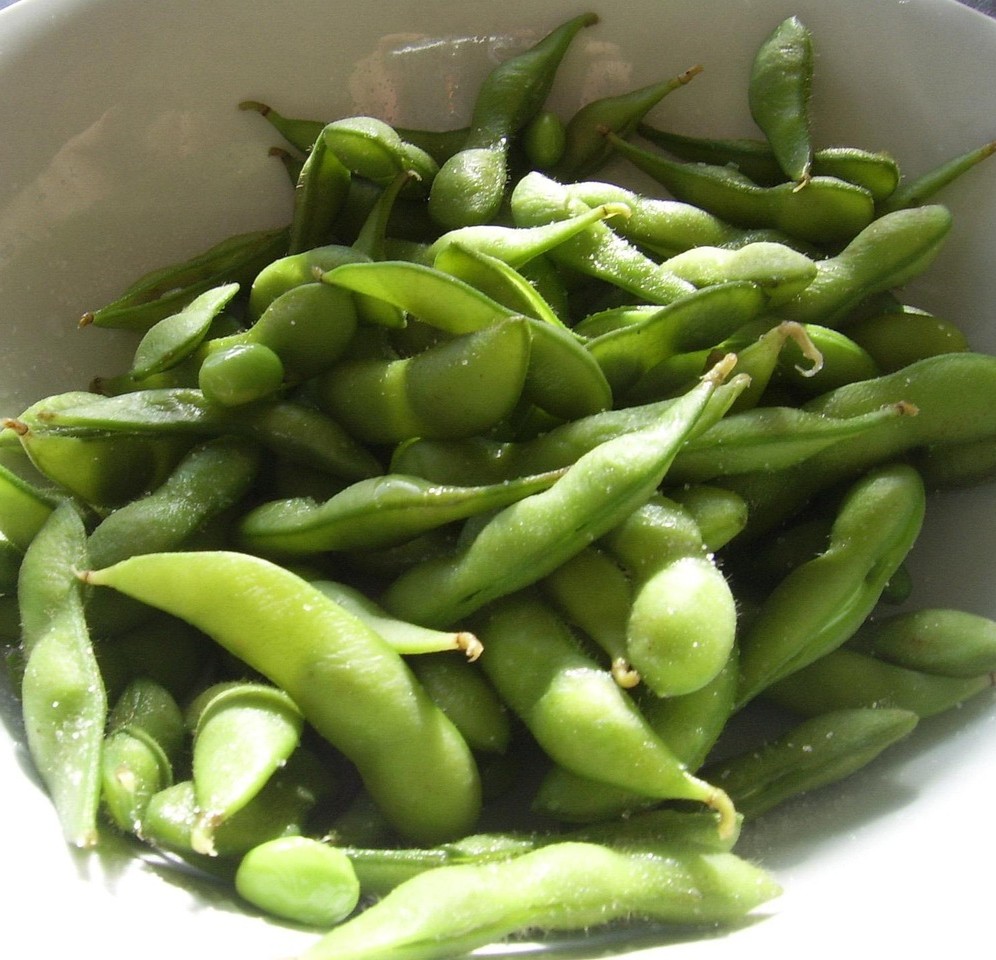 Soya og kræft symboliseret ved en skål med grønne soyabønner i bælg.