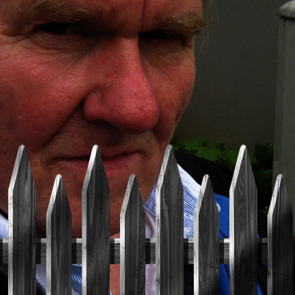 Misundelse og jalousi symboliseret ved en mand der står bag et hegn og ser bøs ud.