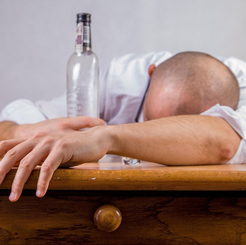 Hvad med alkohol symboliseret ved en mand der har drukket så han sover ind over et bord. med en tom flaske i hånden.