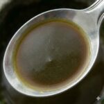 Papaya bladekstrakt symboliseret ved en spiseske med brunlig væske.