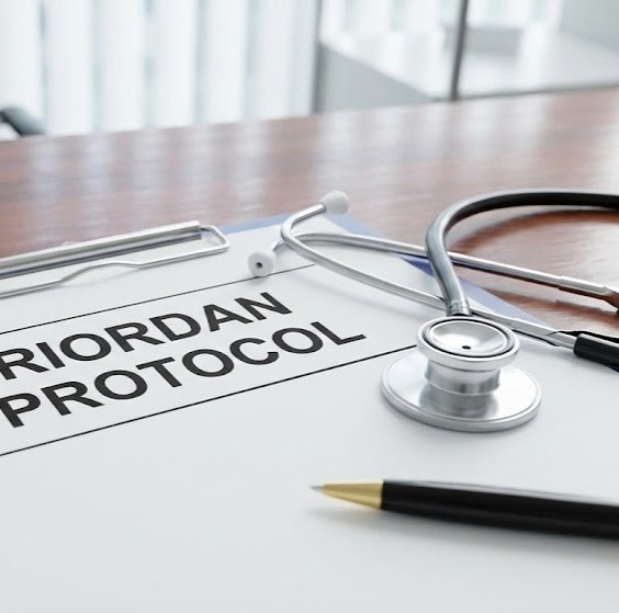 Riordan Protokollen - Højdosis I.V. C-Vitamin symboliseret ved en blok med teksten Riordan Protocol, et stetoskop og en pen.