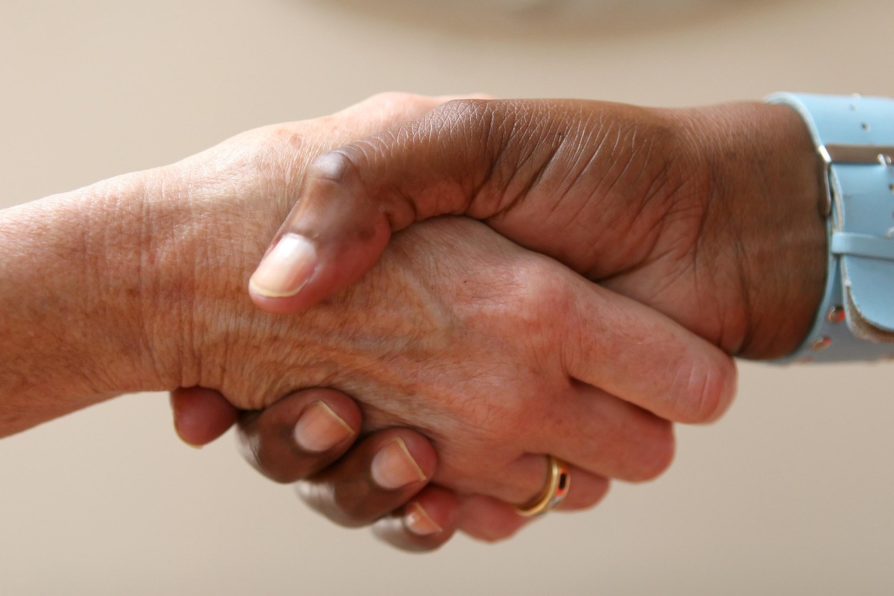 Chemo and radiotherapy support symbolized by two hands meeting in a handshake.