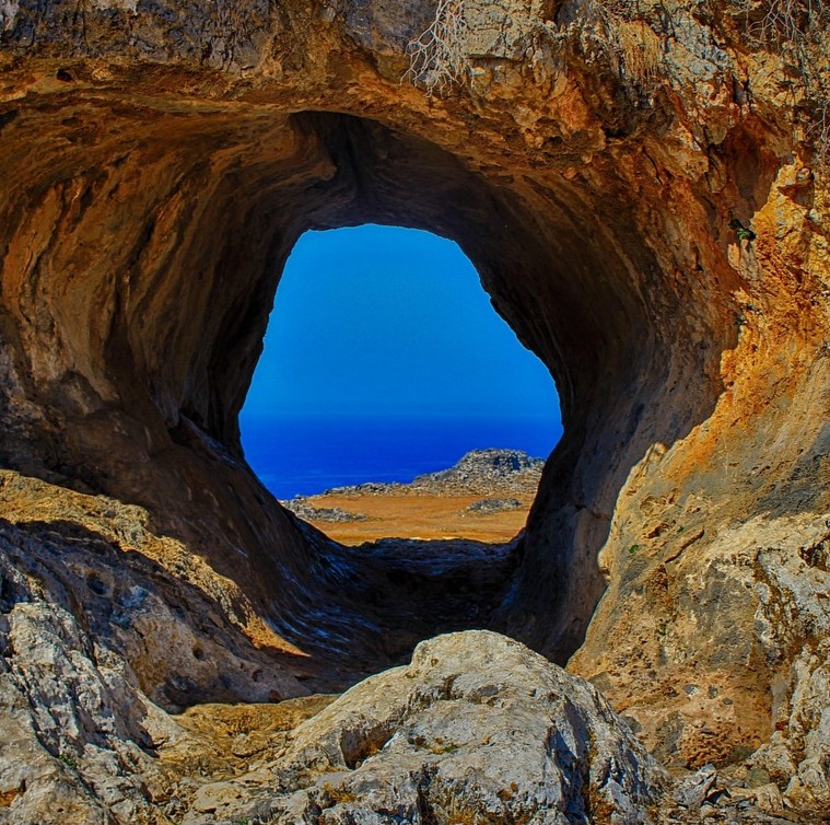 Kemo- og strålestøtte symboliseret ved kig ud gennem hul i klippe mod sandstrand og klart vand og blå himmel.