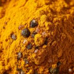 Piperin symboliseret ved curcumin pulver med krystaller og sorte peberkorn iblandet.