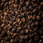 Piperin symboliseret ved sort peberkorn liggende tæt.