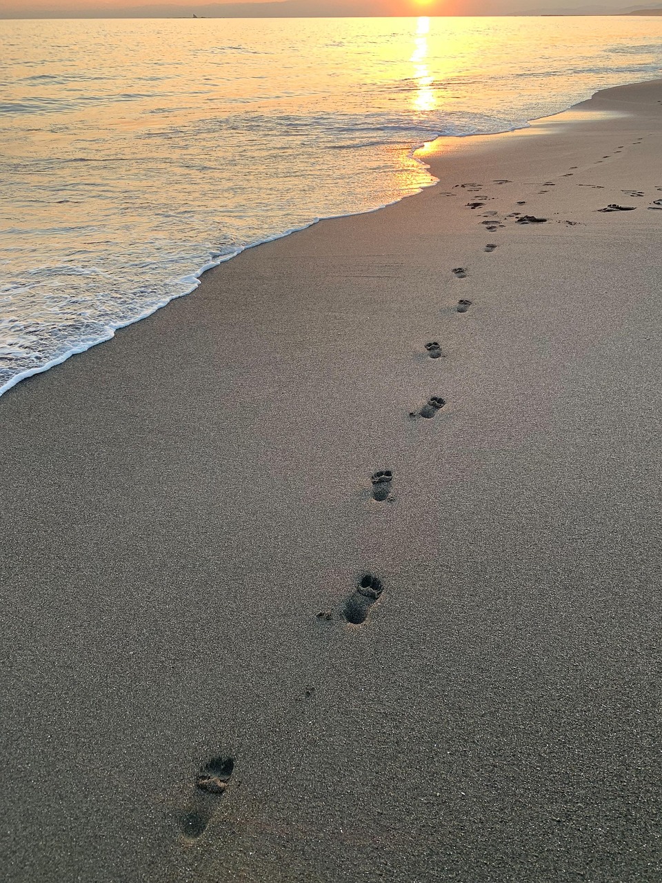 Grounding symboliseret ved en sandstrand med et sæt fodaftryk i sandet.