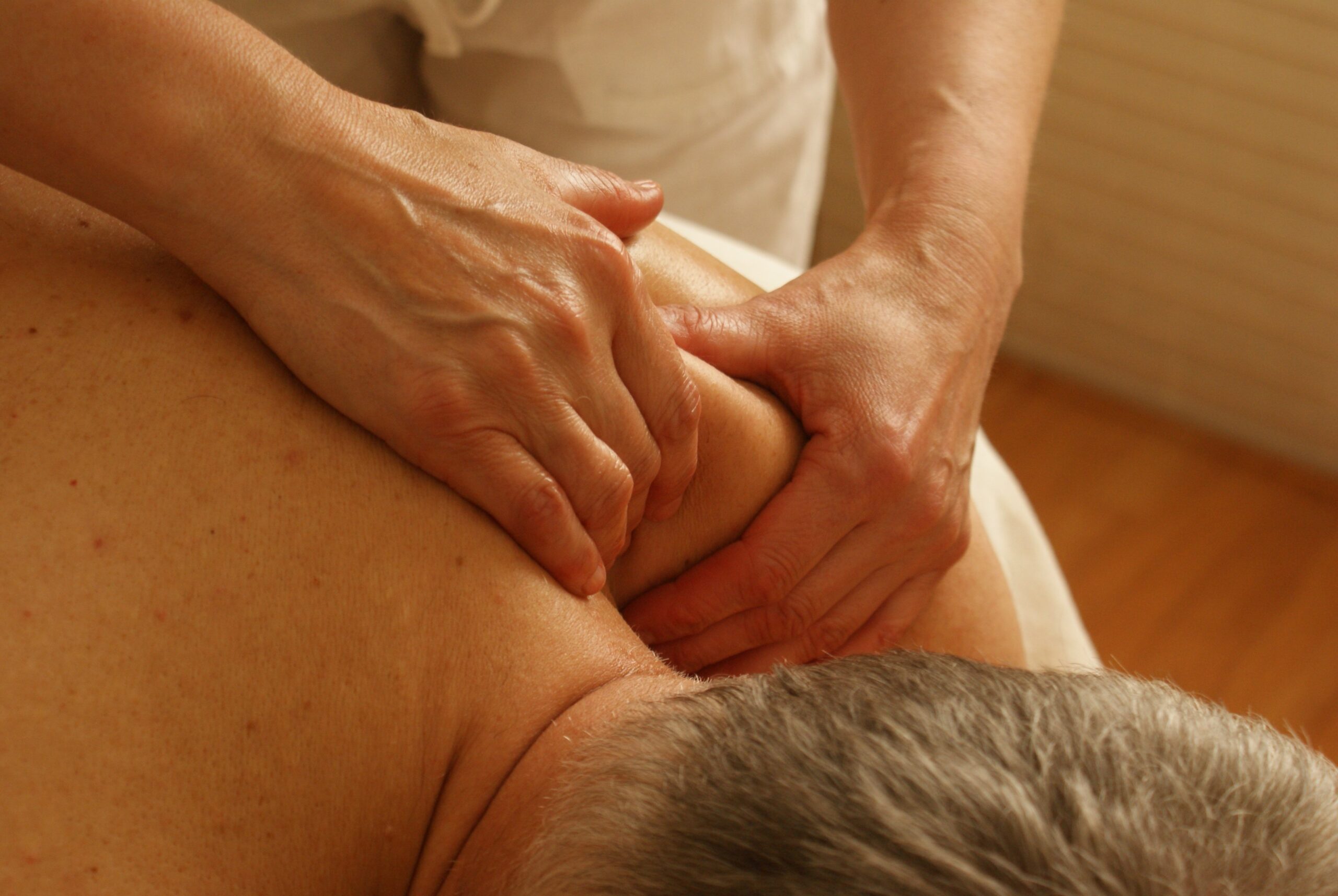 Massage og kræft symboliseret ved en nakke der bliver masseret ved skulderen med et fast greb.