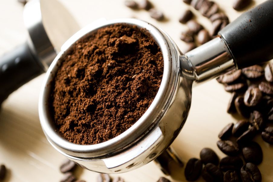 Te og kaffe symboliseret ved et metalfilter med sort kaffe.