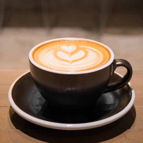 Te og kaffe symboliseret ved brun keramikkop med kaffe og et hjerte i skummet på overfladen.